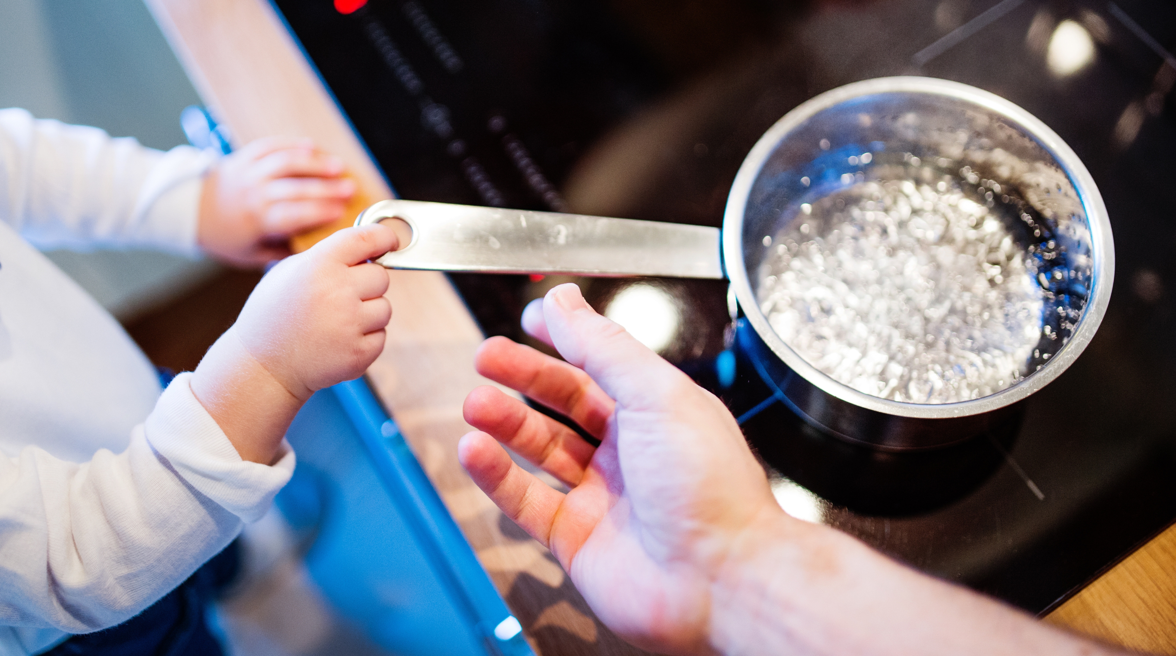 Enfant en situation dangereuse dans la cuisine près d'une casserole d'eau bouillante.